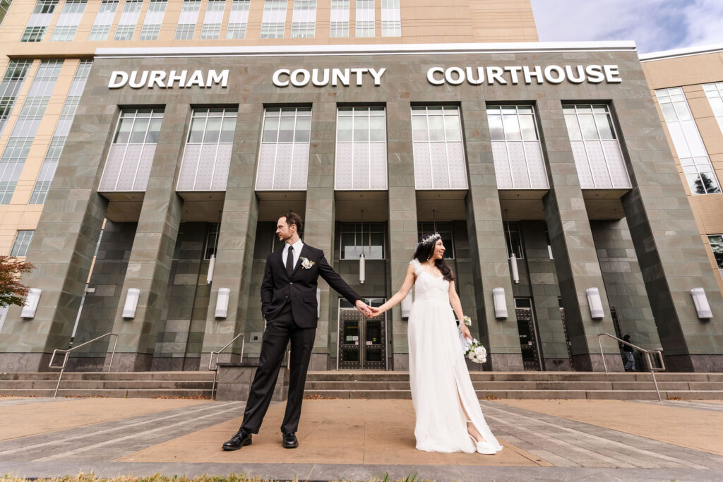 Bride and groom standing on the front steps of the Durham Courthouse with large columns, a popular location for courthouse wedding photos in Durham, North Carolina.